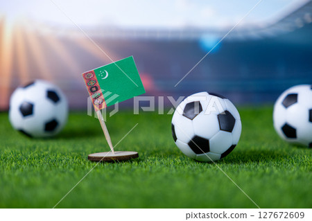 Turkmenistan flag proudly stands on a vibrant green soccer field with mini footballs, symbolizing national team participation in global sports tournaments and pride Turkmenistan flag proudly stands on a vibrant green soccer field with mini footballs, symbolizing national team participation in global sports tournaments and pride 127672609