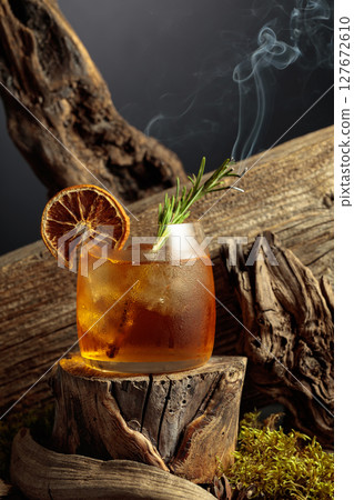 An old-fashioned cocktail over ice on an old wooden stump. 127672610