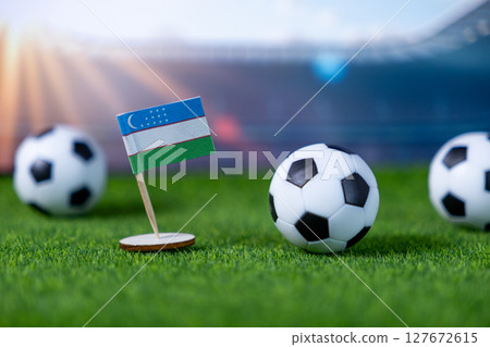 Uzbekistan flag and soccer balls on green grass, symbolizing national pride, team spirit, and global sports competition in a stadium 127672615