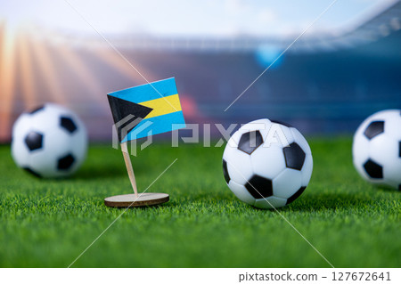Bahamian flag mini stands on green artificial grass with soccer balls, symbolizing the nation's team pride in international football competitions 127672641