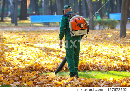 worker in the Park cleans the grass from fallen leaves with the help of a wind turbine worker in the Park cleans the grass from fallen leaves with the help of a wind turbine 127672762