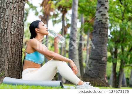 Young Asian woman in activewear sitting under a tree Young Asian woman in activewear sitting under a tree 127673176