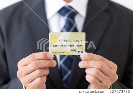 Businessman in a suit holding a credit card 127673726