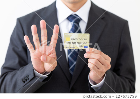 一位西裝革履的商人，手裡拿著信用卡，伸出四根手指 127673759