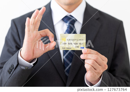 一位西裝革履的商人拿著信用卡，做著圓圈手勢 127673764