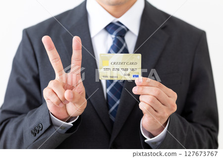 一位西裝革履的商人手持信用卡，做出和平手勢 127673767