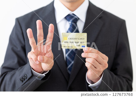 一位西裝革履的商人，手裡拿著信用卡，伸出三根手指 127673768