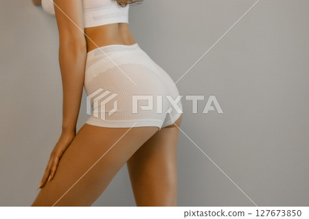 Full lenght portrait of beautiful young fit, slim woman in white underwear, lingerie posing against studio background. Concept of natural beauty, health and body care, spa, anti-cellulite, femininity 127673850