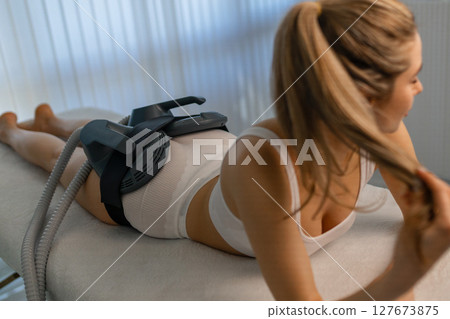 Woman getting treatment on buttocks to burn fat, build muscles and remove cellulite. Professional beauty salon 127673875