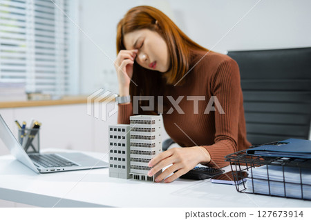 Asian woman stressed over credit card debt, holding bills in frustration. Financial anxiety and economic burden concept in a realistic lifestyle setting. Asian woman stressed over credit card debt, holding bills in frustration. Financial anxiety and economic burden concept in a realistic lifestyle setting. 127673914
