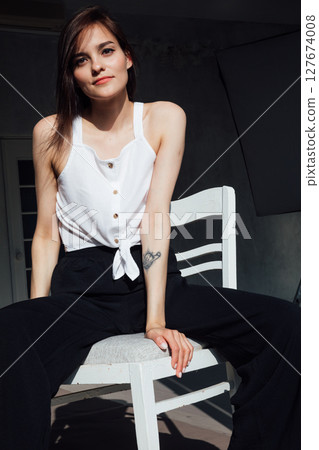 fashionable woman in black clothes sitting on chair in room fashionable woman in black clothes sitting on chair in room 127674008