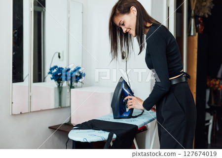 Woman house wife ironing washed clothes with iron on board 127674019
