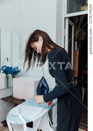 Woman house wife ironing washed clothes with iron on board Woman house wife ironing washed clothes with iron on board 127674020
