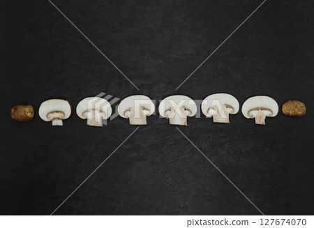 Abstract composition of split up brown champignons mushrooms placed in line on stone background surface Abstract composition of split up brown champignons mushrooms placed in line on stone background surface 127674070
