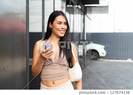 Modern Asian Woman Using Phone Outdoors in City 127674136