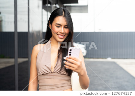 Modern Asian Woman Using Phone Outdoors in City 127674137
