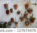 Flower pots hanging on an old white wall 127674476