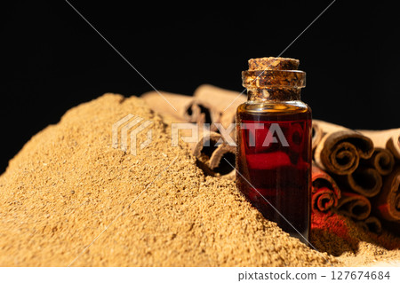 Natural cinnamon essential oil in a glass bottle close-up. 127674684