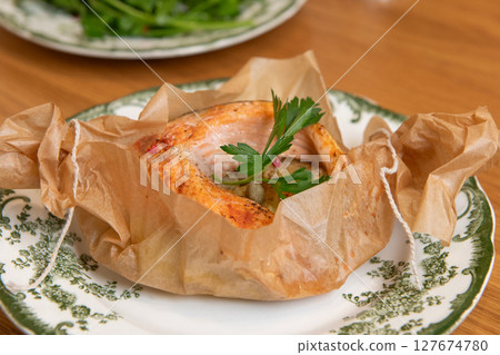 Salmon fillet baking in parchment paper on plate 127674780