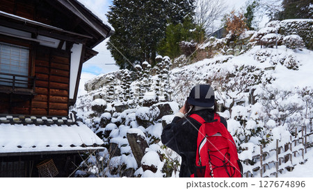 A young female tourist photographing the snowy scenery of Magome-juku, a tourist spot on the Nakasendo road in winter 127674896