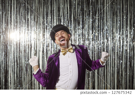 Excited funny showman dancing at disco party on shiny silver foil background 127675342