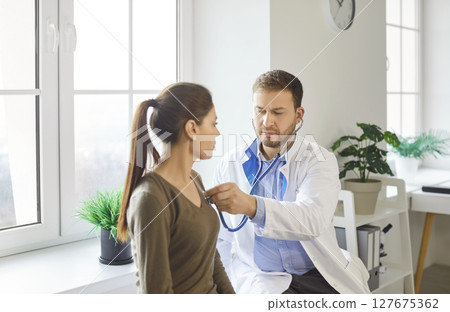 Focused Doctor Examining Patient With Stethoscope Focused Doctor Examining Patient With Stethoscope 127675362