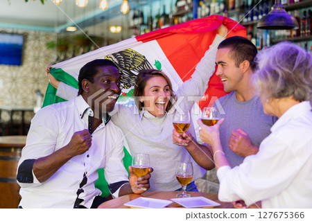 Happy international sport fans waving mexico flag while watching football match and drinking beer in the pub 127675366