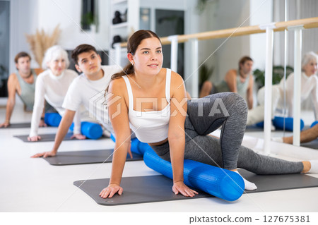 Group of different people doing exercises with roller Group of different people doing exercises with roller 127675381