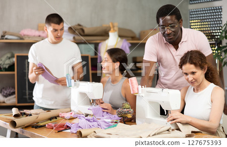 Experienced sewing instructor overseeing students in fashion course 127675393