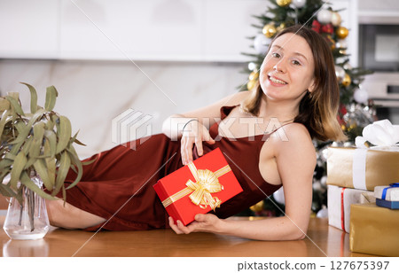 Woman poses with Christmas presents at home Woman poses with Christmas presents at home 127675397