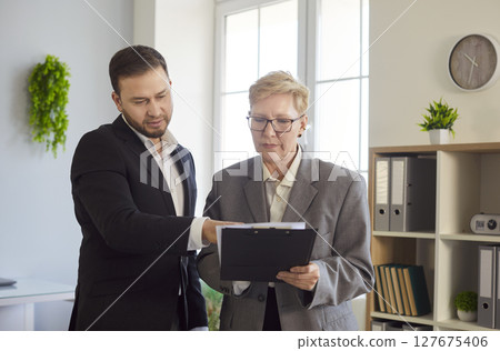 Business people, man and woman looking down at document, focused, serious and engaged in reviewing 127675406