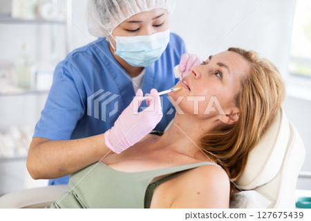 Young doctor perfoming face injecting Young doctor perfoming face injecting 127675439