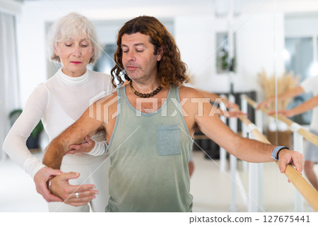 Elderly woman and adult man practicing ballet at barre Elderly woman and adult man practicing ballet at barre 127675441