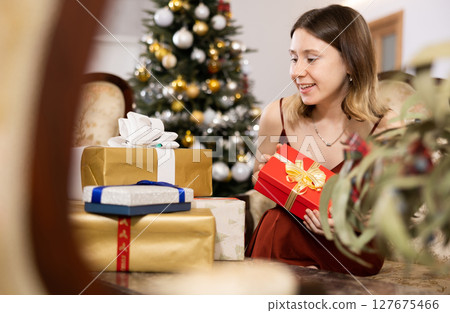 Happy young woman prepares Christmas presents Happy young woman prepares Christmas presents 127675466