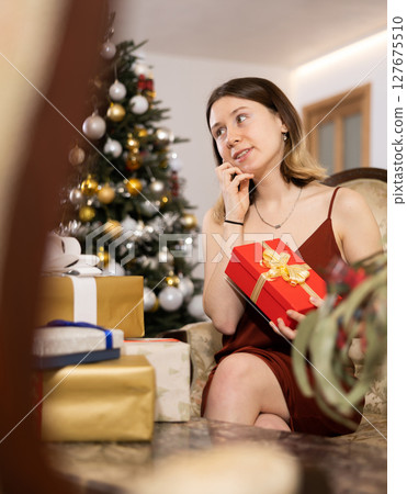 Happy young woman prepares Christmas presents 127675510