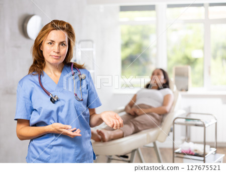 Woman beautician wearing blue overall posing in clinic of esthetic medicine 127675521