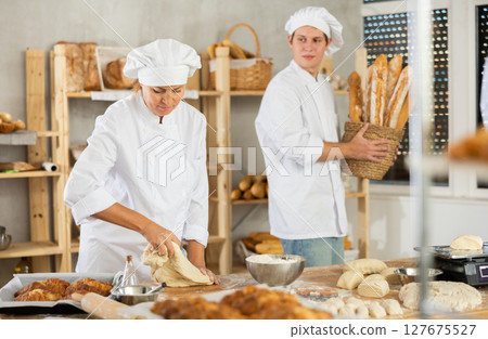 Woman works in bakery as baker, kneads dough, works with flour. Woman works in bakery as baker, kneads dough, works with flour. 127675527