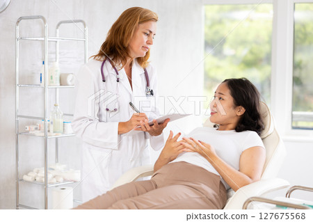 Professional beauty specialist giving documents to patient 127675568