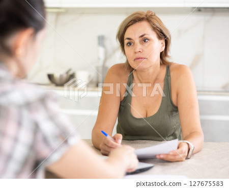 An insurance agent tells woman the terms of property and life insurance 127675583