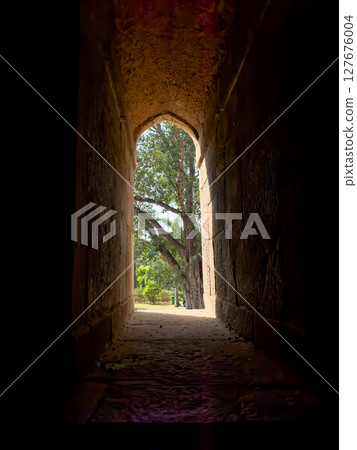 Window arch with stone frame, creating a narrow passage between light and shadow. Historic, 127676004