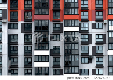 Building with red, black, and white apartment facade in geometric grid pattern. Modern modular 127676058