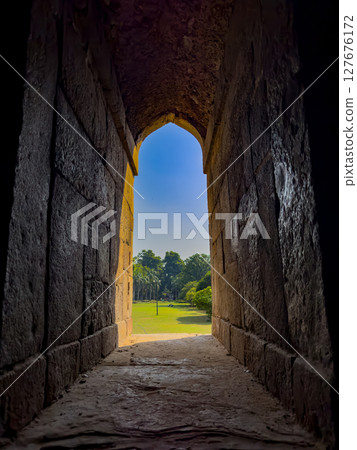 Stone arch window opening to a peaceful garden. Framed view of green nature, trees, and soft grass, 127676172