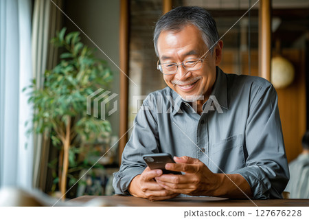 老人家正在家中享受使用智慧型手機的樂趣（AI 生成的圖像） 127676228