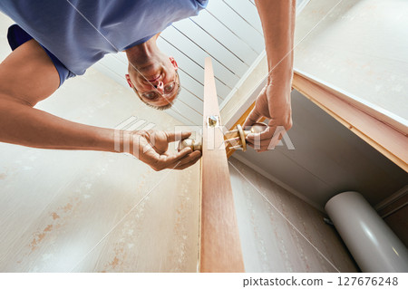 Door knobs with latch and lock mechanism are being attached on both sides of door by installer to complete assembly and enable door operation. 127676248