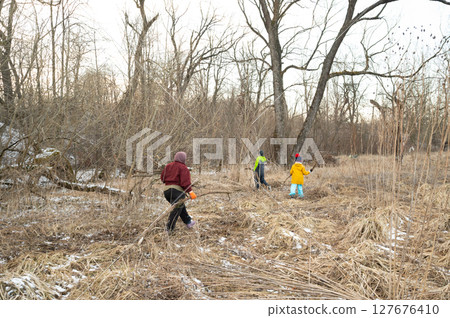 Families exploring nature in a winter landscape while cleaning up the overgrown area, fostering love for the outdoors and promoting community care for the environment Families exploring nature in a winter landscape while cleaning up the overgrown area, fostering love for the outdoors and promoting community care for the environment 127676410