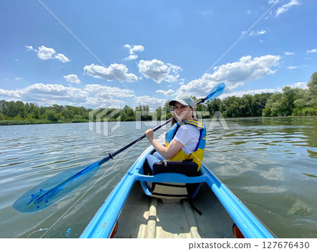 Happy woman in kayak with paddle, summer day, kayaking on the river. 127676430