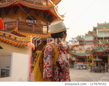 Woman Exploring Colorful Streets Near Buddhist Temples in Bangkok. Young traveler walking through the vibrant streets of Bangkok, admiring intricate temple details and lively surroundings.. Woman Exploring Colorful Streets Near Buddhist Temples in Bangkok. Young traveler walking through the vibrant streets of Bangkok, admiring intricate temple details and lively surroundings.. 127676542