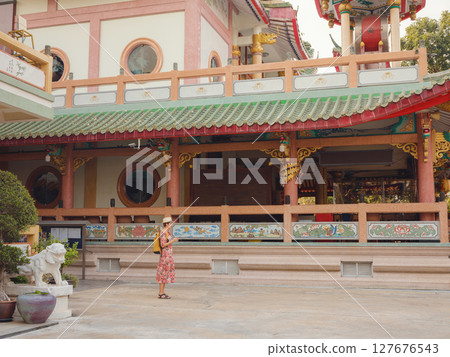 Woman Exploring Colorful Streets Near Buddhist Temples in Bangkok. Woman tourist exploring colorful alleys near historic Buddhist temples in Bangkok, enjoying the cultural atmosphere. 127676543