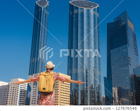 Young woman exploring Qasr Al Hosn Park in Abu Dhabi. Surrounded by lush greenery and historical landmarks, she enjoys the serene atmosphere and Emirati heritage in heart of city. 127676548