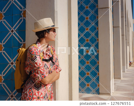 Young woman exploring Qasr Al Hosn Park in Abu Dhabi. Surrounded by lush greenery and historical landmarks, she enjoys the serene atmosphere and Emirati heritage in heart of city. 127676551